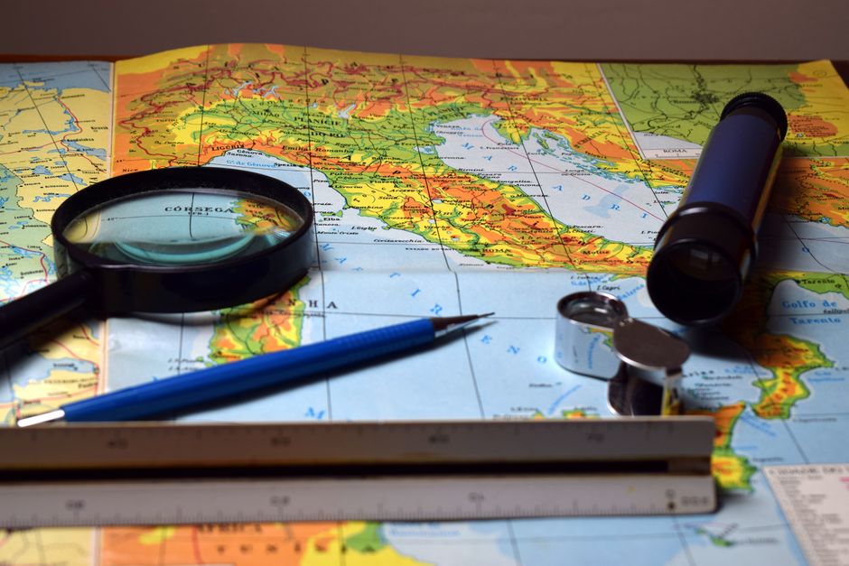 Magnifying glass and tools on a colorful map, perfect for travel and exploration themes.