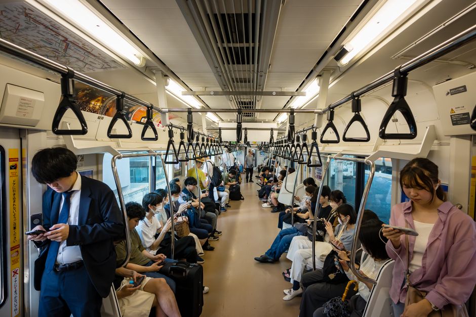 A snapshot of everyday life showing passengers on a crowded subway train in Japan.